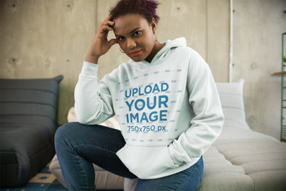 Hoodie Mockup of a Woman Sitting on a Modern Couch