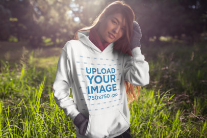 Hoodie Mockup of a Young Woman Standing in a Meadow