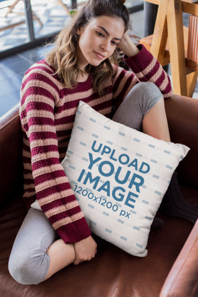 Mockup of a Woman Holding a Pillow Sitting on a Leather Sofa