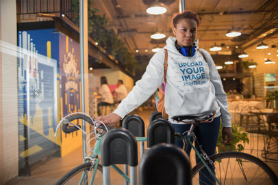 Pullover Hoodie Mockup of a Woman Standing by Her Bike at Night