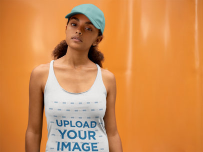 Mockup of a Woman Wearing a Racerback Tank Top Against an Orange Wall
