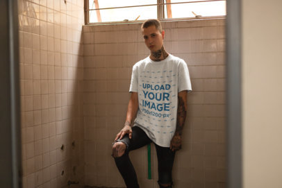 T-Shirt Mockup of a Punk Man with Tattoos Leaning Against a Tiles Wall