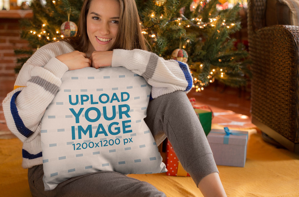 Mockup of a Cute Woman Holding a Pillow in Front of the Christmas Tree