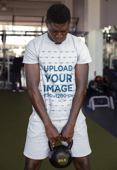 Round Neck Tee Mockup of a Strong Man Holding a Kettlebell at the Gym