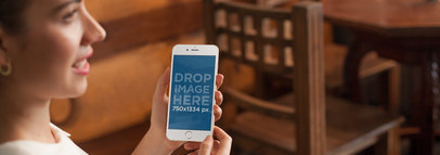 Mockup of a Young Lady Using her iPhone 6 at a Restaurant