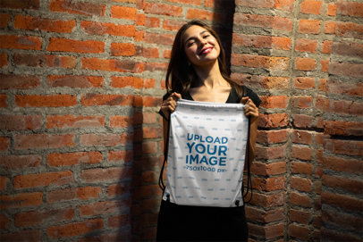 Mockup of a Happy Young Woman Showing Off Her Cool Drawstring Bag