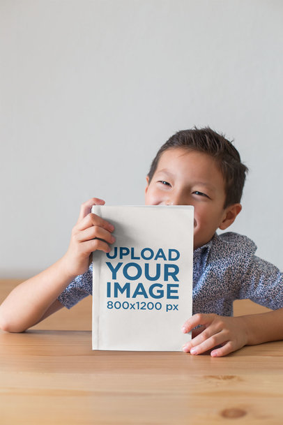 Back to School Book Mockup of a Little Boy Smiling and Showing off His Book