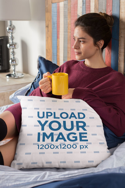 Pillow Mockup of a Woman Sitting Cozily On Her Bed Drinking Tea