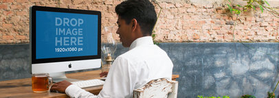 Mockup of a Young Latino Man Working on an iMac