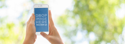 Mockup of a Woman at the Park Lying on the Grass Holding her iPhone 6 