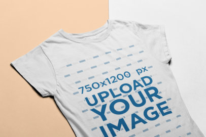Angled View Mockup of a Women's Tee Lying on a Two-Color Surface