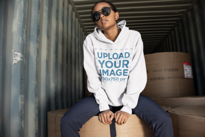Mockup of a Cool Woman Wearing a Hoodie Sitting on Large Round Packages