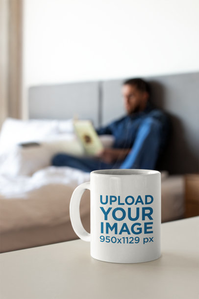 Coffee Mug Mockup with a Man Reading a Book in the Background