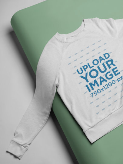 Mockup of a Women's Sweatshirt Lying on a Folded Colored Cardboard