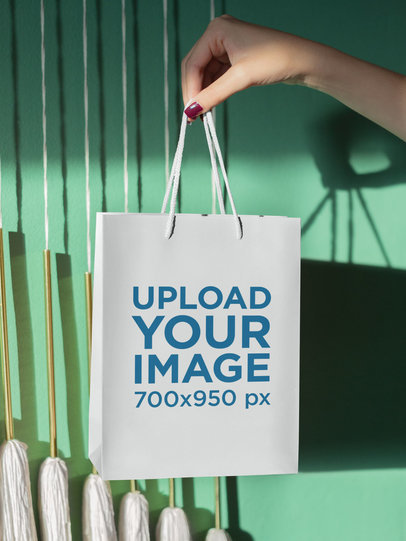 Mockup of a Woman's Hand Holding up a Gift Bag