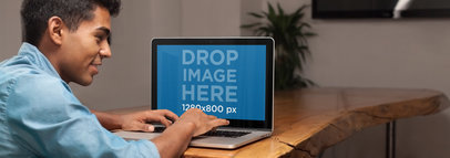 Mockup of a Young Man Working on a Macbook Pro in a Conference Room