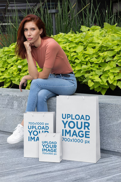 Gift Bag Mockup Featuring a Woman Sitting on a Stone Bench