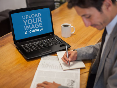 Laptop Mockup Featuring a Businessman at the Office Working on his Laptop