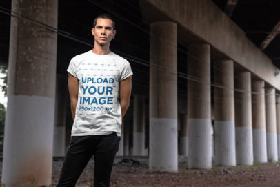 T-Shirt Mockup of a Serious Man Standing Under an Overpass Bridge