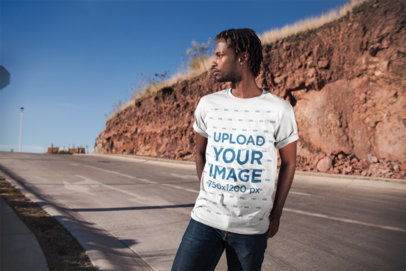 Mockup of a Man Wearing a Camping T-Shirt on a Highway