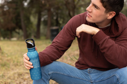 Mockup of a Man Holding His Aluminum Water Bottle in a Meadow