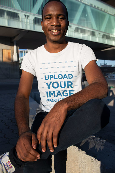 Mockup of a Happy Man Wearing a Tee Sitting Outside