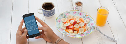 Mockup of a Woman Using an iPhone 6 During Breakfast at a Local Cafe