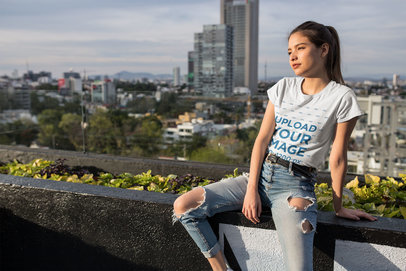 T-Shirt Mockup of a Pretty Woman Sitting on a Roof Terrace 24647