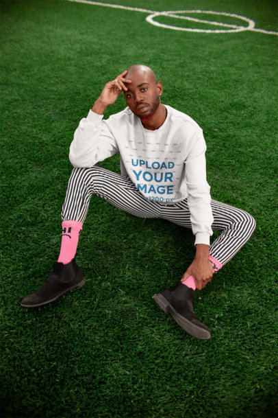 Mockup of a Stylish Man Wearing a Crewneck Sweater Sitting on Grass 21690