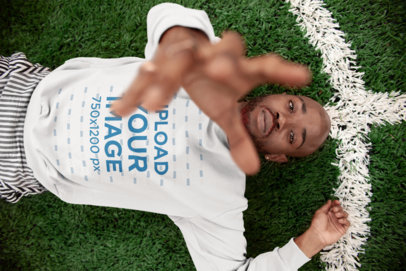 Sweatshirt Mockup of a Cool Man Reaching for the Camera Lying on Grass 21688