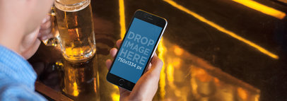 Mockup of a Man at a Bar Using an iPhone 6 and Having a Beer