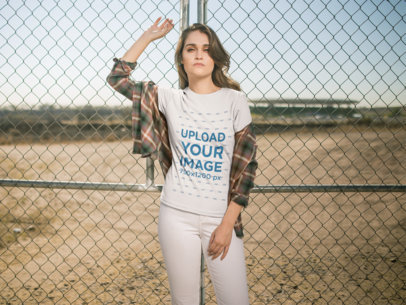 T-Shirt Mockup of a Woman Leaning on a Fence Outdoors