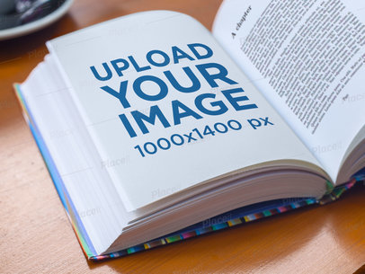Mockup Featuring a Book Lying Open on Top of a Wooden Table