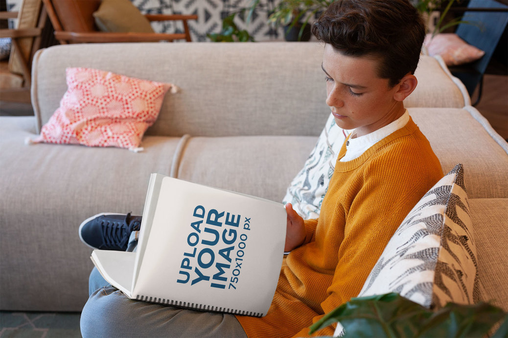 School Notebook Mockup Featuring a Young Boy Sitting Comfortably on a Couch