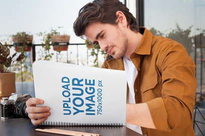 Mockup of a Man Writing Attentively in His School Notebook