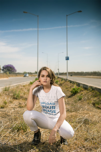 T-Shirt Mockup of a Woman in a Crouching Pose Outdoors