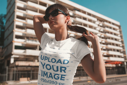 T-Shirt Mockup of a Woman with a Ponytail and Sunglasses on the Street