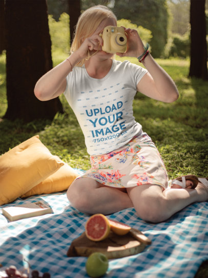 T-Shirt Mockup of a Woman Taking a Photo with a Polaroid Outdoors