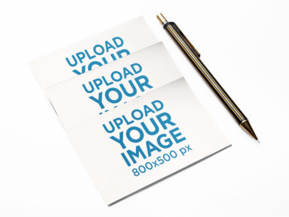 Mockup of 3 Business Cards Lying Next to a Metallic Pen