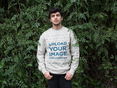 Mockup of a Serious Man Wearing a Sweatshirt in Front of a Large Hedge 18197