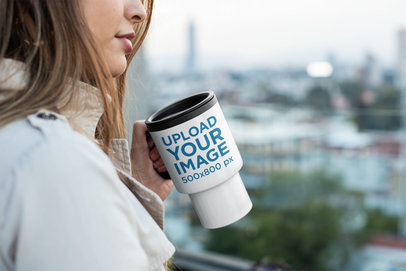 Mockup of a Woman Holding a Travel Mug Outside