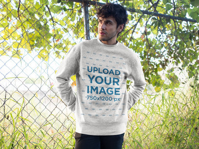 Heather Sweatshirt Mockup of a Man Standing Against a Fence Outdoors