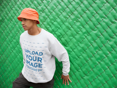 Sweatshirt Mockup of a Man Leaning Against a Green Fence
