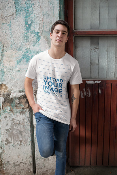 Mockup of a Man Wearing a Loose Tee While Leaning Against an Old Wall