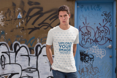 T-Shirt Mockup of a Man Standing by a Graffiti Art Wall