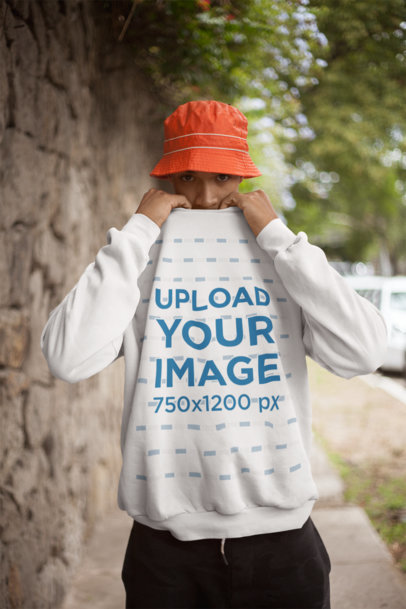 Sweatshirt Mockup of a Man Covering his Face by a Stone Wall