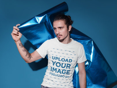T-Shirt Mockup of a Young Man Holding a Metallic Paper Foil 18526