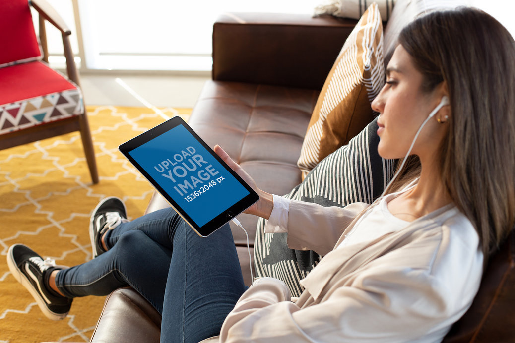 iPad 6 Mockup of a Woman with White Earphones Listening to a Podcast
