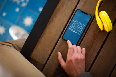 Mockup of an Iphone X on a Wooden Bench Reproducing a Podcast 24808