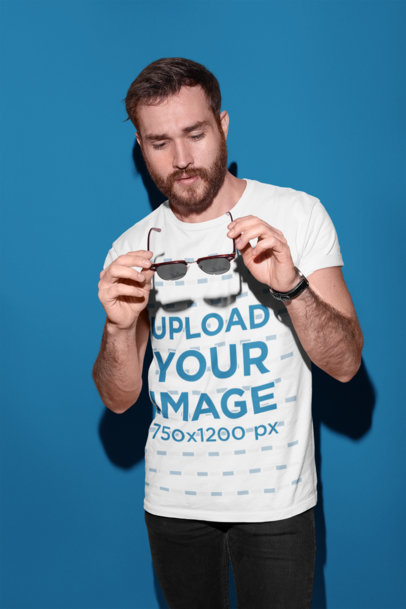 Round Neck Tee Mockup of a Man Holding Sunglasses in a Photo Studio